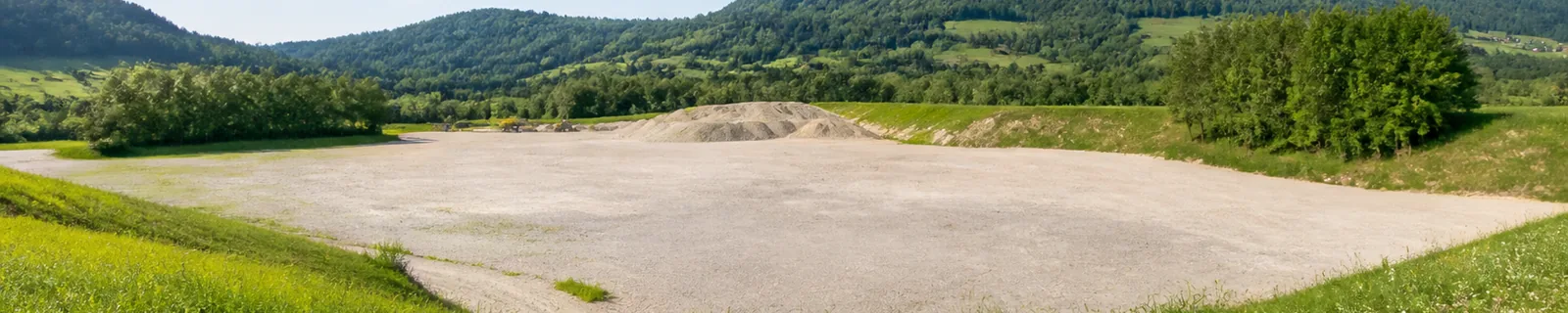 Helle österreichische Rohstofflandschaft mit Kiesfläche und begrünten Rändern